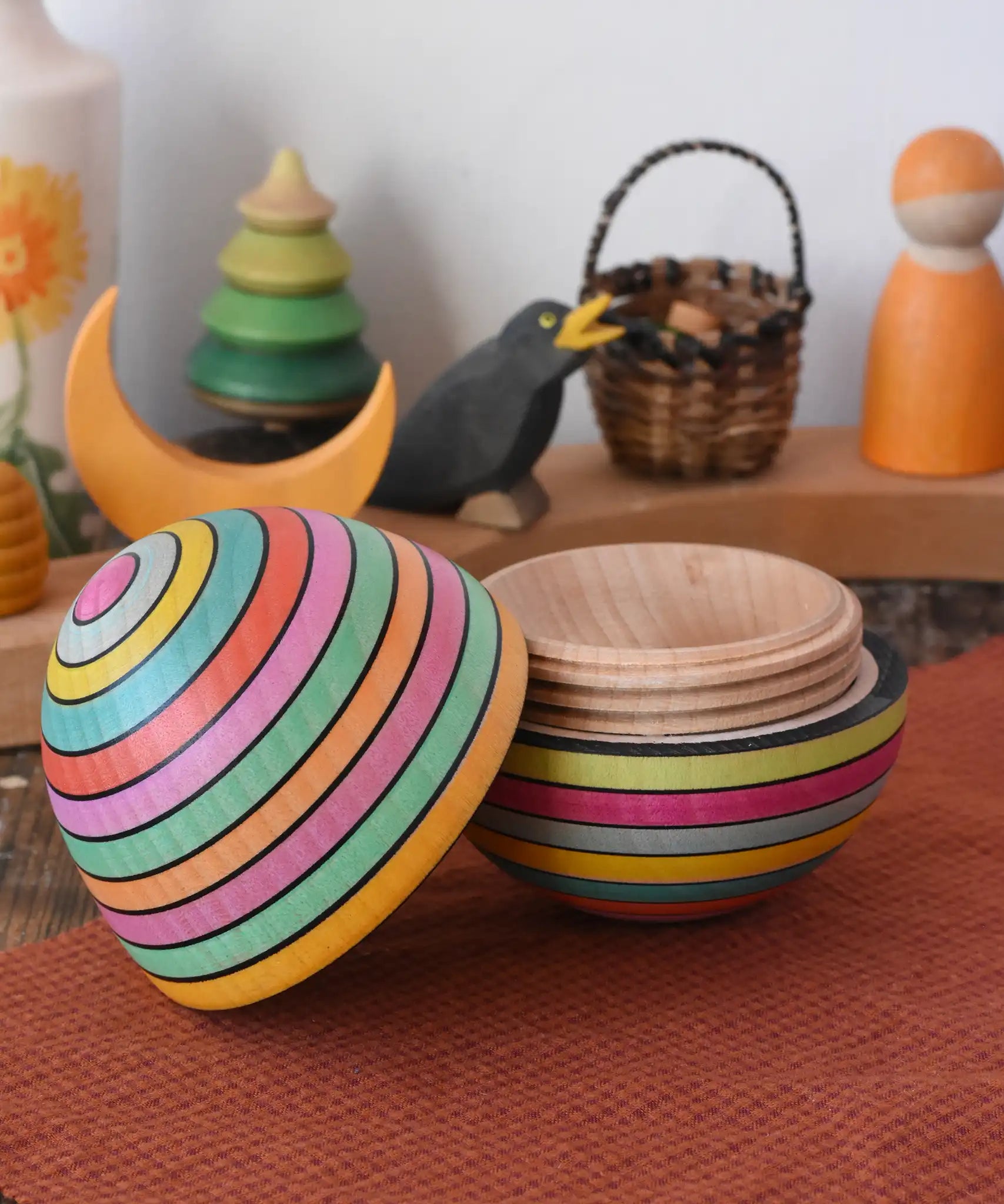 Mader Kreiselmanufaktur roly-poly wooden egg in Spring opened and placed on a wooden surface in the Babipur playroom. The wooden thread can be seen on the sides of the egg.