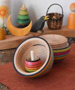 Mader Kreiselmanufaktur roly-poly wooden egg in Spring opened with a rainbow turn over spinning top placed inside in the Babipur playroom.