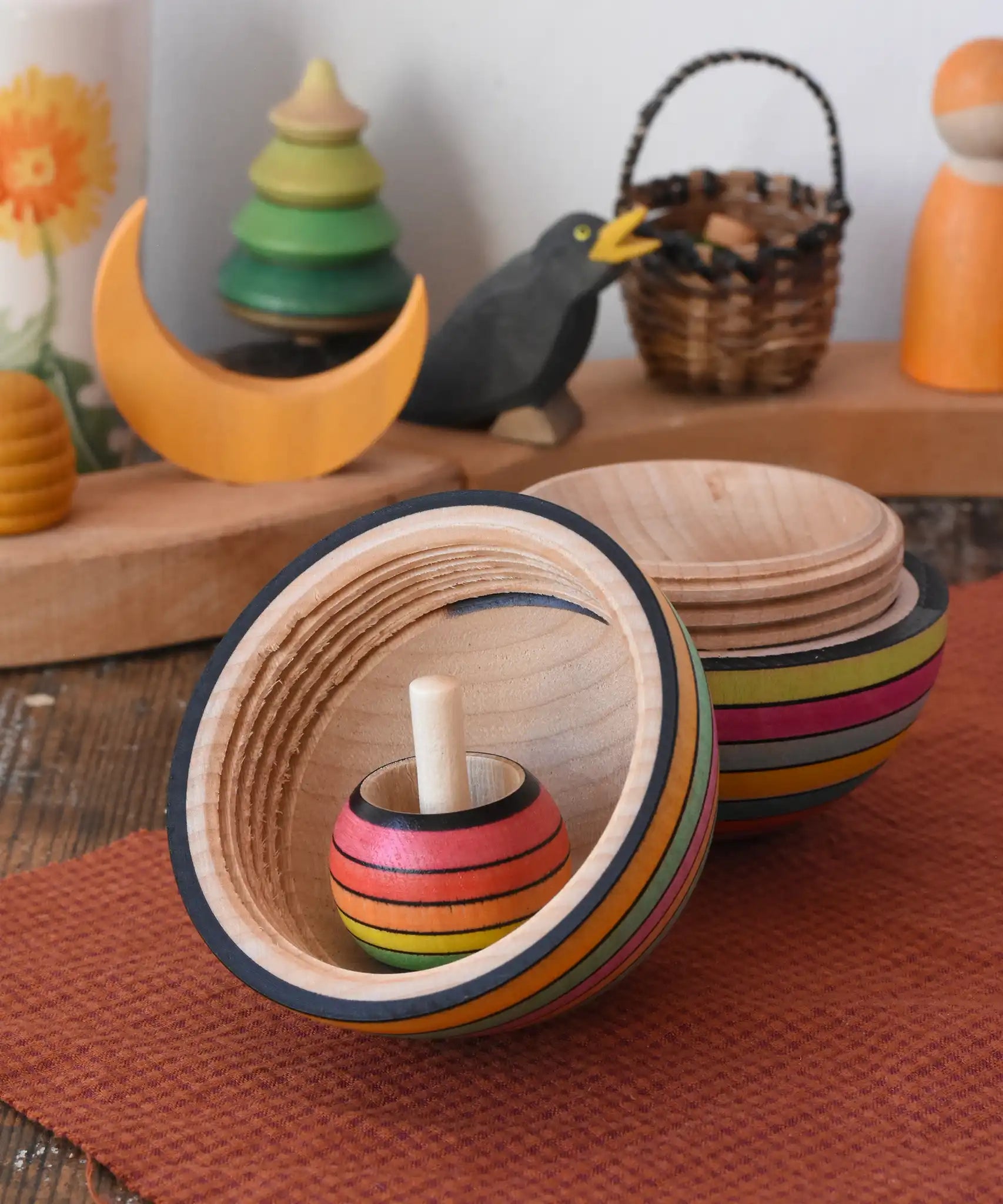Mader Kreiselmanufaktur roly-poly wooden egg in Spring opened with a rainbow turn over spinning top placed inside in the Babipur playroom.