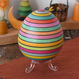 Mader Kreiselmanufaktur roly-poly wooden egg in Spring stripe colours placed on the clear display stand in the Babipur playroom.