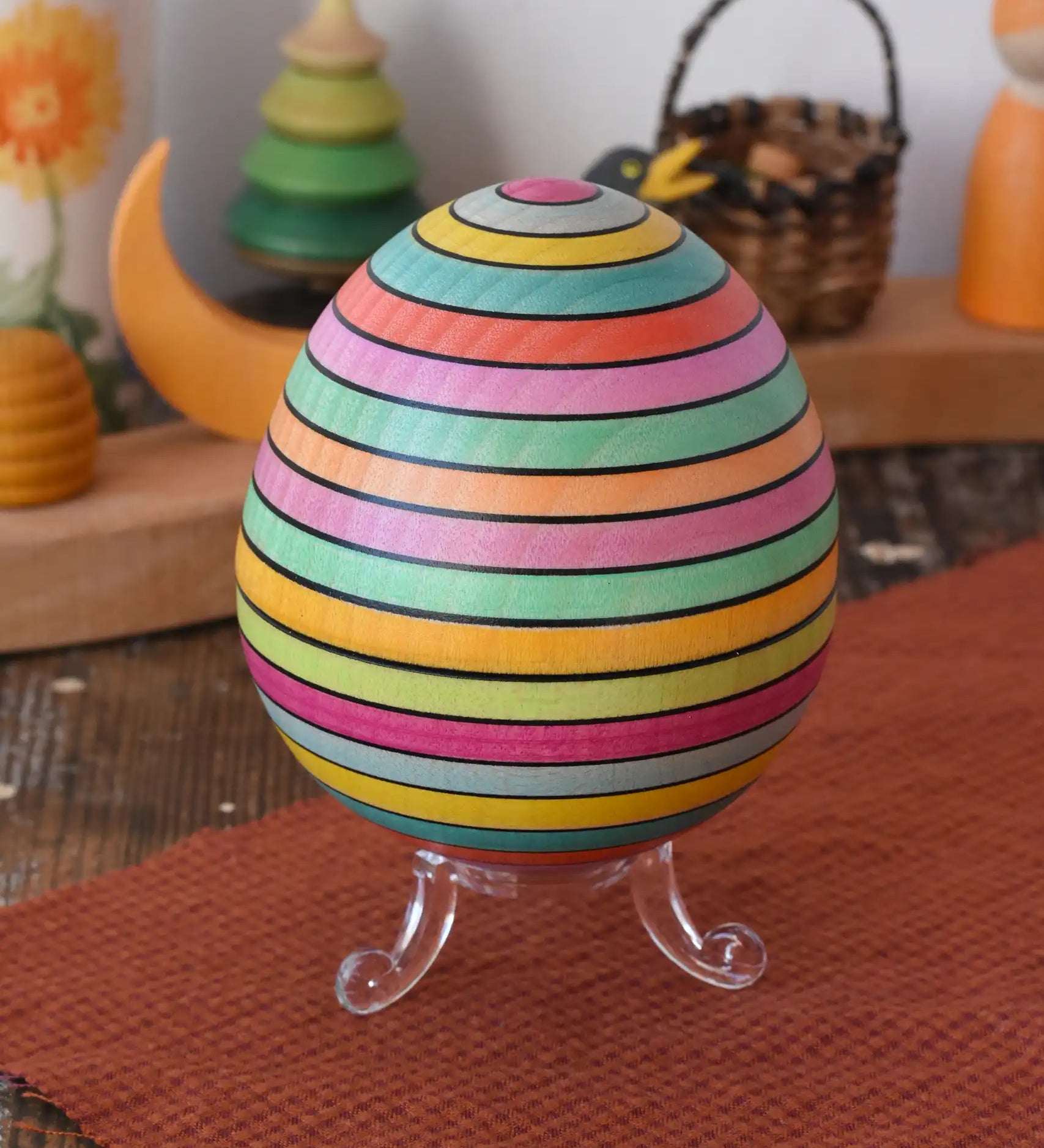 Mader Kreiselmanufaktur roly-poly wooden egg in Spring stripe colours placed on the clear display stand in the Babipur playroom.