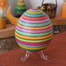 Mader Kreiselmanufaktur roly-poly wooden egg in Spring stripe colours placed on the clear display stand in the Babipur playroom.