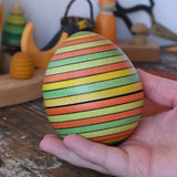 Mader Kreiselmanufaktur roly-poly wooden egg in Summer in an adult's hand.