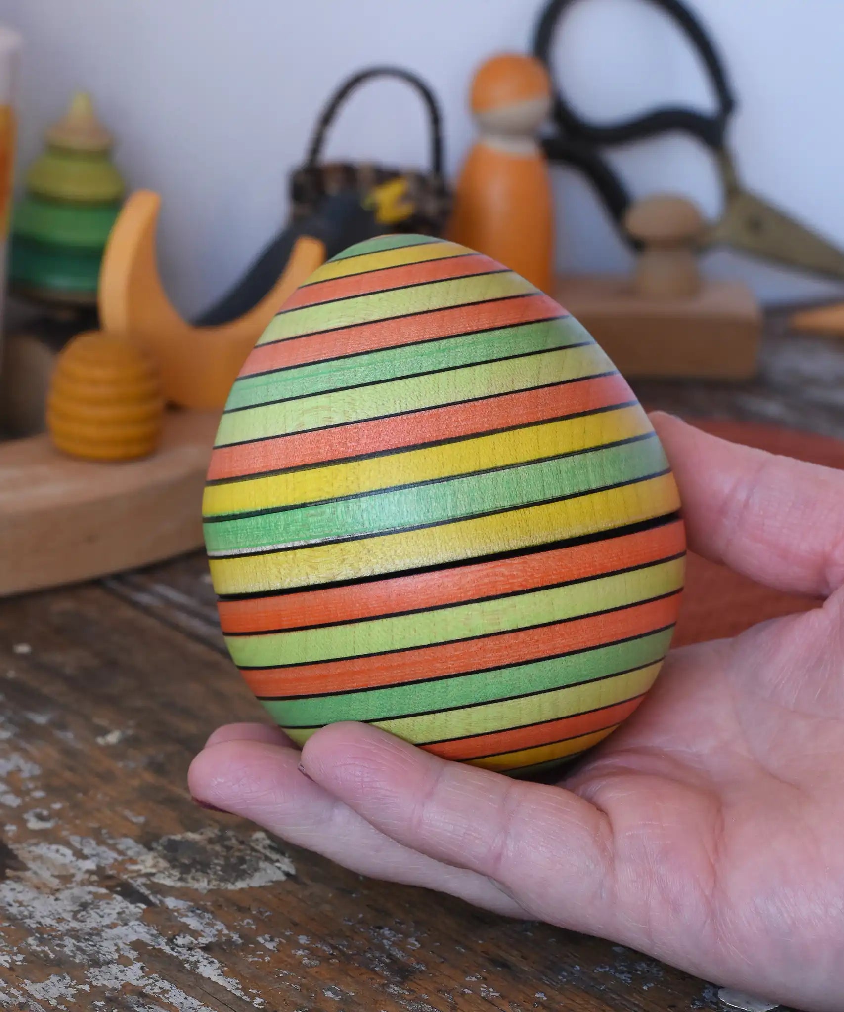 Mader Kreiselmanufaktur roly-poly wooden egg in Summer in an adult's hand.