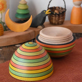 Mader Kreiselmanufaktur roly-poly wooden egg in Summer opened and placed on a wooden surface in the Babipur playroom. The wooden thread can be seen on the sides of the egg.