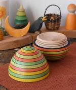 Mader Kreiselmanufaktur roly-poly wooden egg in Summer opened and placed on a wooden surface in the Babipur playroom. The wooden thread can be seen on the sides of the egg.