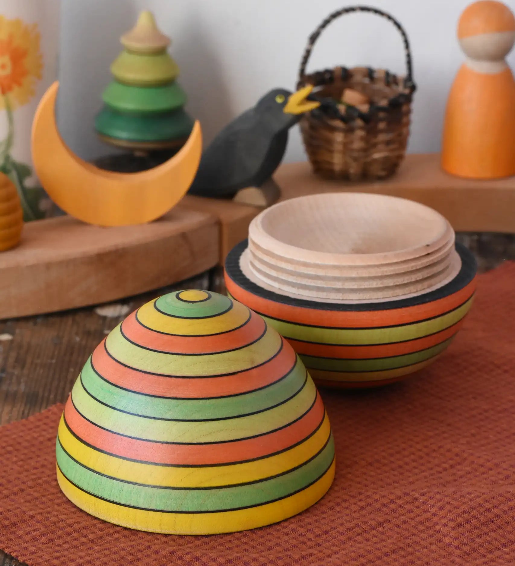 Mader Kreiselmanufaktur roly-poly wooden egg in Summer opened and placed on a wooden surface in the Babipur playroom. The wooden thread can be seen on the sides of the egg.