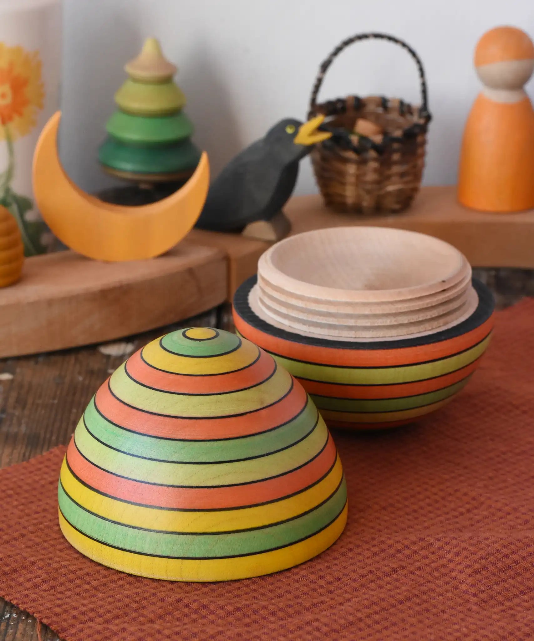 Mader Kreiselmanufaktur roly-poly wooden egg in Summer opened and placed on a wooden surface in the Babipur playroom. The wooden thread can be seen on the sides of the egg.