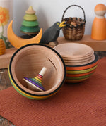 Mader Kreiselmanufaktur roly-poly wooden egg in Summer colours opened with a rainbow rallye spinning top placed inside in the Babipur playroom.
