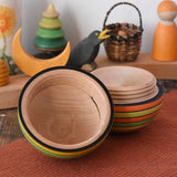 Mader Kreiselmanufaktur roly-poly wooden egg in Summer opened and placed on a wooden surface in the Babipur playroom. The wooden thread can be seen on the sides of the egg.