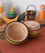 Mader Kreiselmanufaktur roly-poly wooden egg in Summer opened and placed on a wooden surface in the Babipur playroom. The wooden thread can be seen on the sides of the egg.
