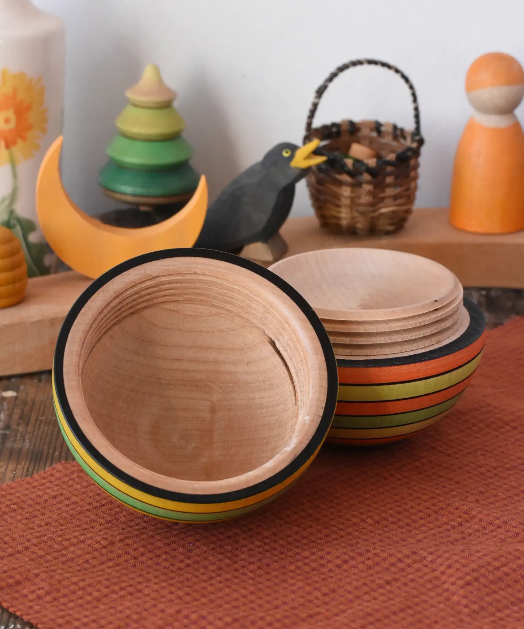 Mader Kreiselmanufaktur roly-poly wooden egg in Summer opened and placed on a wooden surface in the Babipur playroom. The wooden thread can be seen on the sides of the egg.