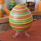 Mader Kreiselmanufaktur roly-poly wooden egg in Summer stripe colours placed on the clear display stand in the Babipur playroom.
