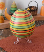 Mader Kreiselmanufaktur roly-poly wooden egg in Summer stripe colours placed on the clear display stand in the Babipur playroom.