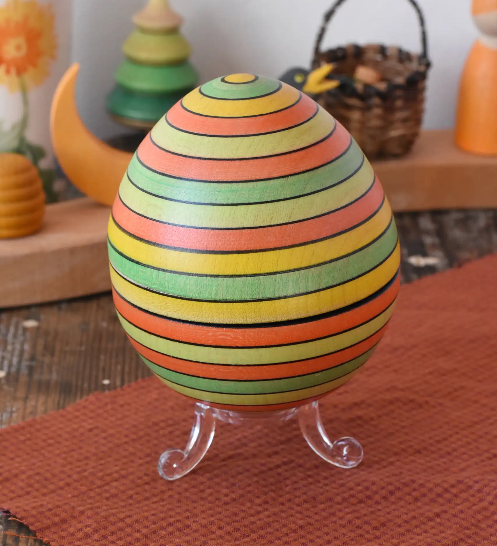 Mader Kreiselmanufaktur roly-poly wooden egg in Summer stripe colours placed on the clear display stand in the Babipur playroom.
