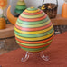 Mader Kreiselmanufaktur roly-poly wooden egg in Summer stripe colours placed on the clear display stand in the Babipur playroom.
