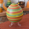 Mader Kreiselmanufaktur roly-poly wooden egg in Summer stripe colours placed on the clear display stand in the Babipur playroom.