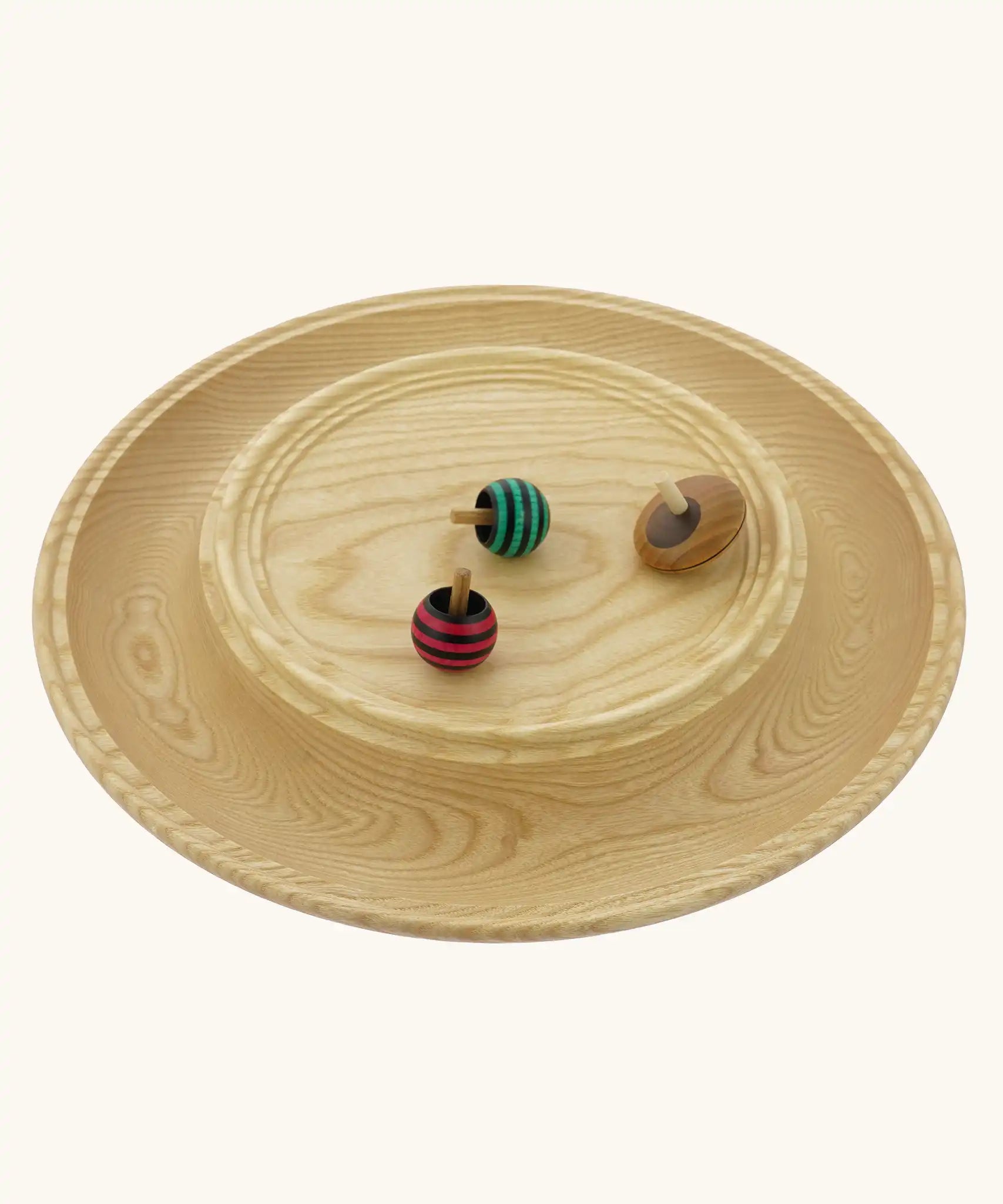 Mader Kreiselmanufaktur Rondell Ash Wood 40cm Spinning Plate with three wooden spinning tops placed on it.