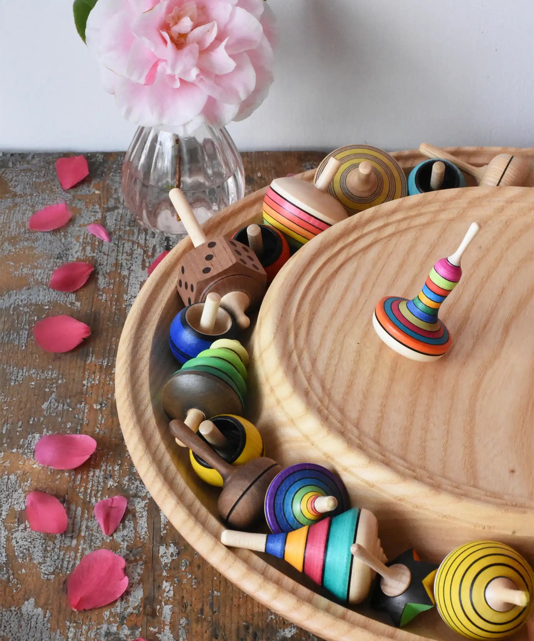 Mader Kreiselmanufaktur 40cm Rondell Ash Wood Spinning Plate placed on a wooden surface in the Babipur playroom. Monalotte spinning top placed on the top with other spinning tops filling bottom part of the plate. 