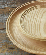 Close up of the Mader Kreiselmanufaktur Rondell Ash Wood 40cm Spinning Plate placed on a wooden surface in the Babipur playroom.