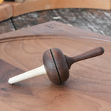 Mader Kreiselmanufaktur Salto Totale Walnut / Hornbeam Spinning Top placed on a walnut wood spinning plate in the Babipur playroom.
