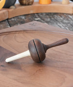 Mader Kreiselmanufaktur Salto Totale Walnut / Hornbeam Spinning Top placed on a walnut wood spinning plate in the Babipur playroom.