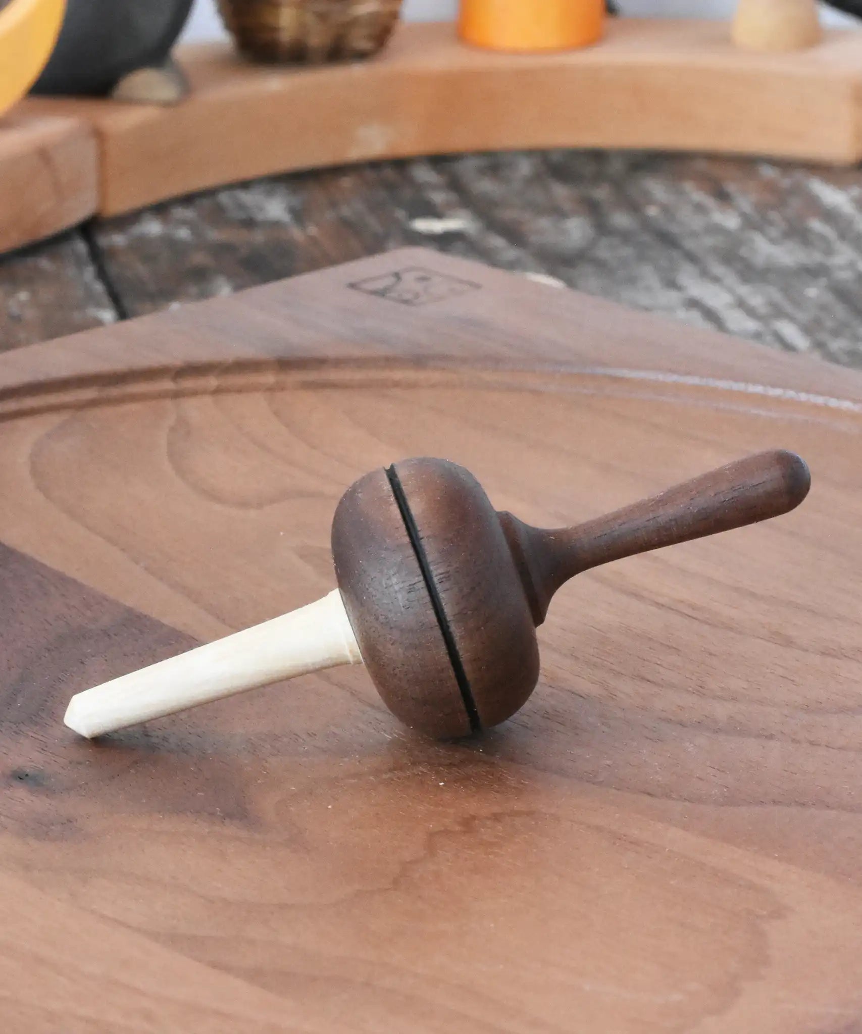 Mader Kreiselmanufaktur Salto Totale Walnut / Hornbeam Spinning Top placed on a walnut wood spinning plate in the Babipur playroom.
