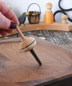 Mader Salto Totale wooden spinning top held upright on a walnut spinning plate in the Babipur playroom.
