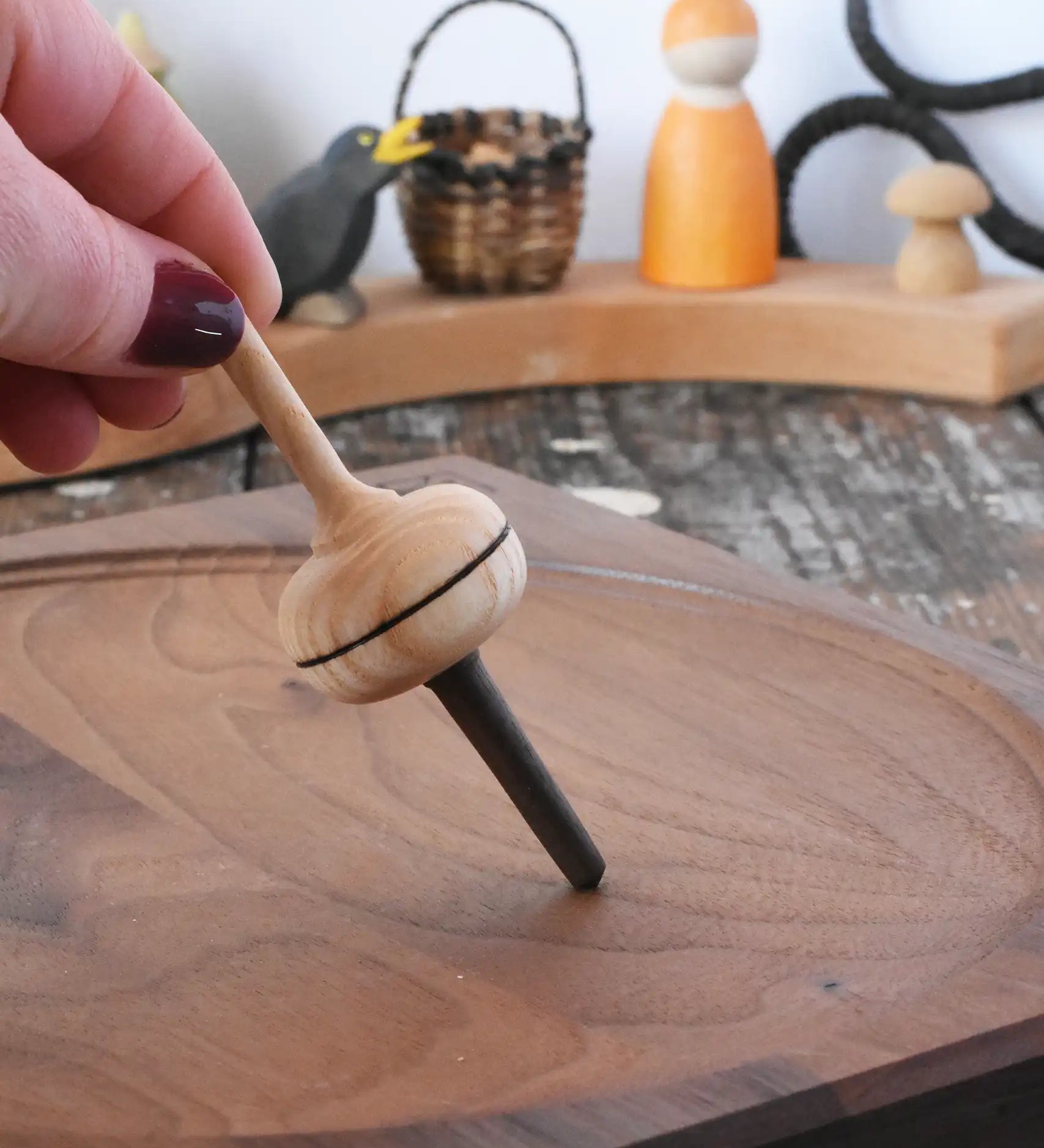 Mader Salto Totale wooden spinning top held upright on a walnut spinning plate in the Babipur playroom.