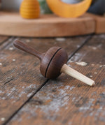 Mader Kreiselmanufaktur Salto Totale Walnut / Hornbeam Spinning Top placed on a desk in the Babipur playroom.