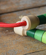 Close up of handle tops on the Mader Skipping Rope with Green Handles placed on a wooden board in the Babipur playroom. 