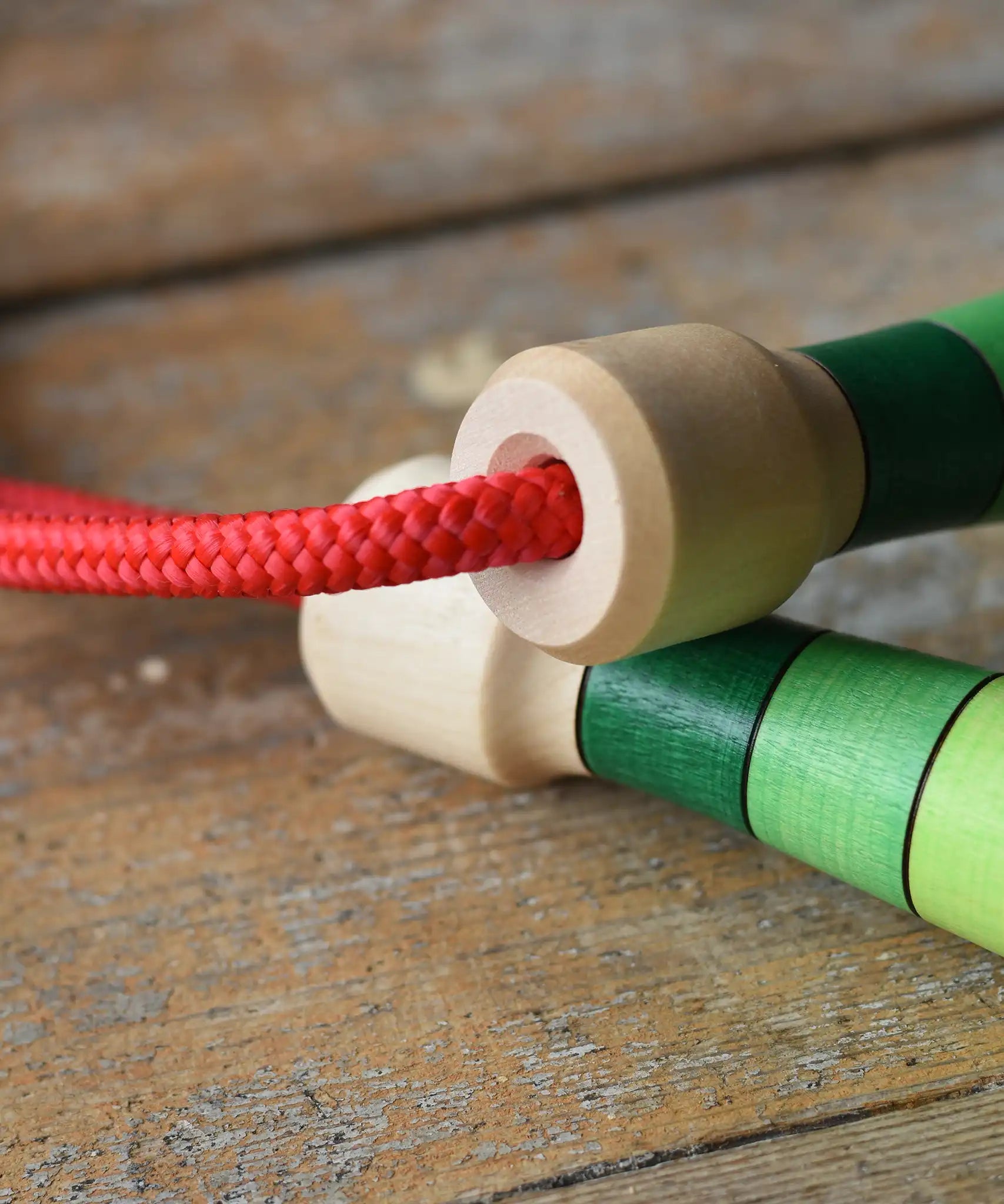 Close up of handle tops on the Mader Skipping Rope with Green Handles placed on a wooden board in the Babipur playroom. 