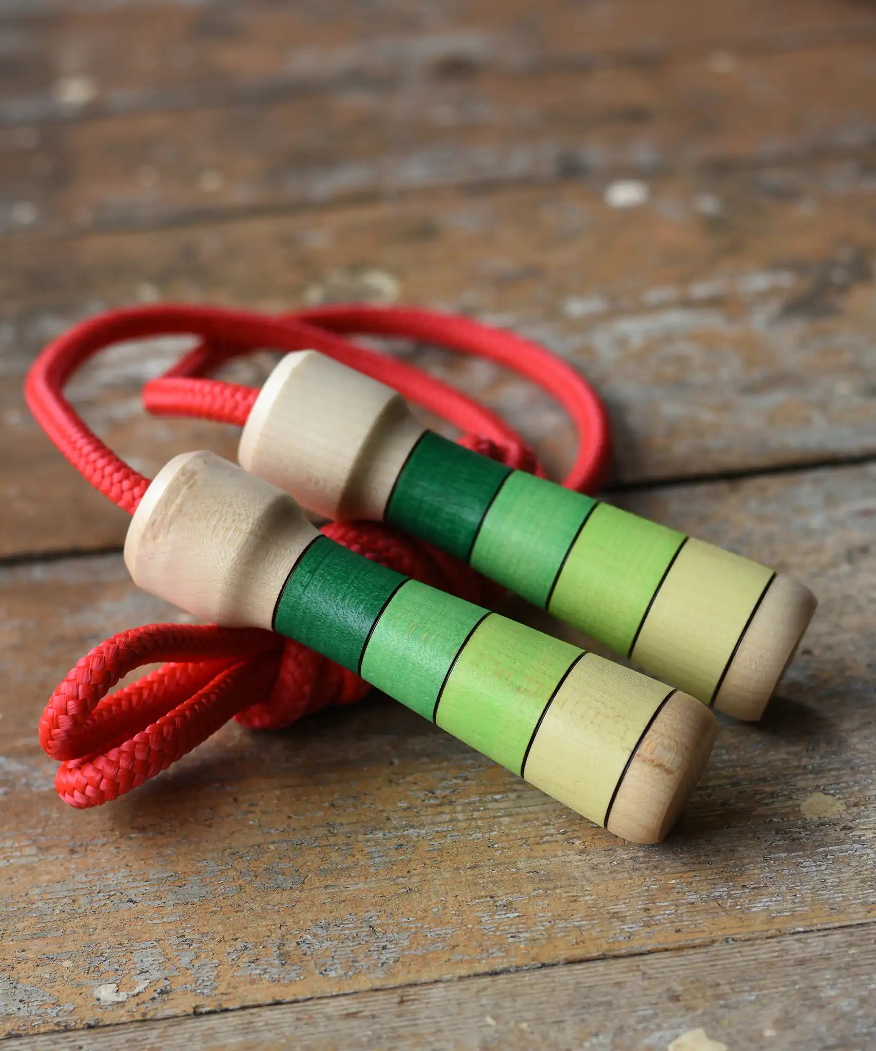 Mader Skipping Rope with Green Handles placed on a wooden board in the Babipur playroom. 