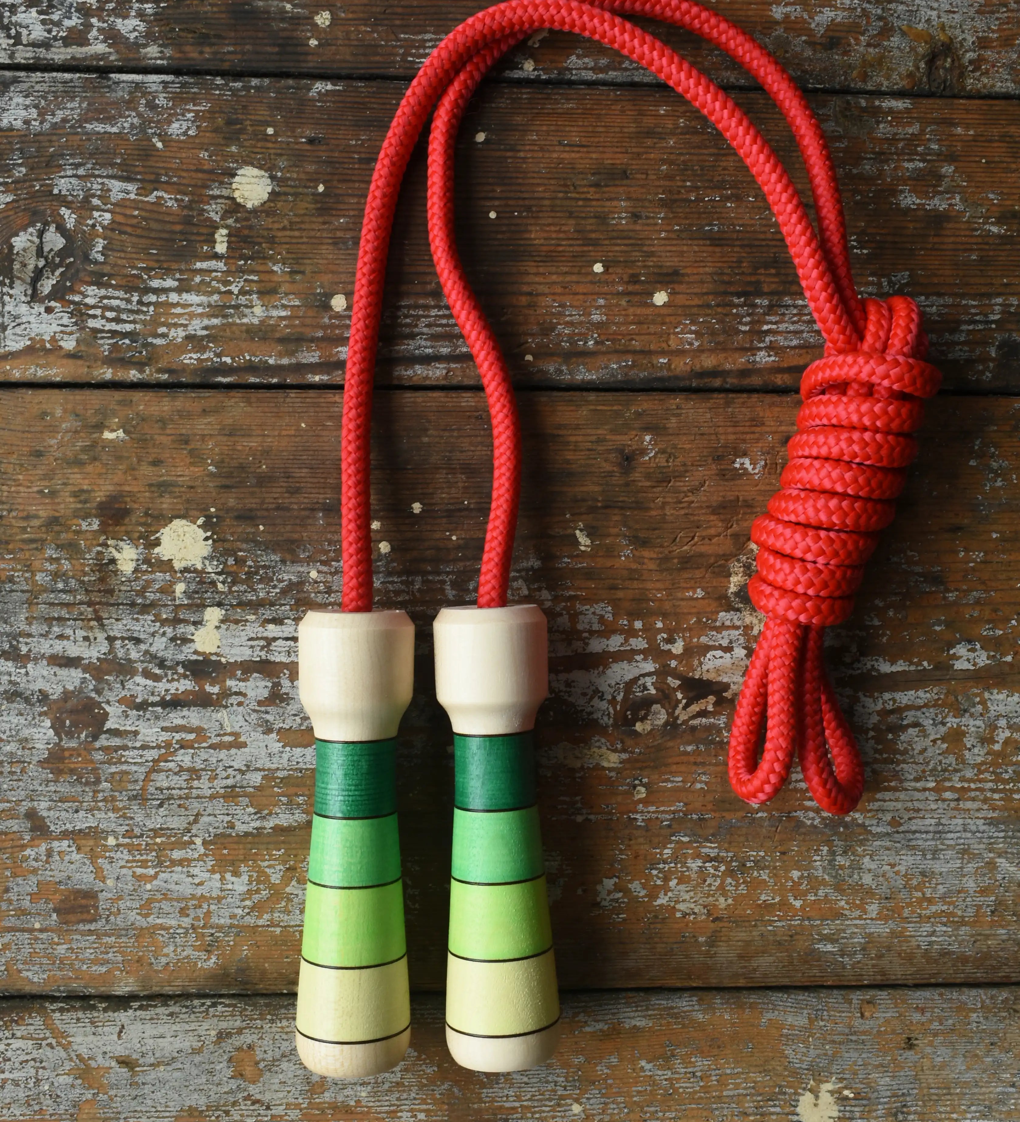 Mader Skipping Rope with Green Handles placed on a wooden board in the Babipur playroom. 