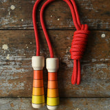 Mader Kreiselmanufaktur Children's Skipping Rope with Orange Handles placed on a wooden surface in the Babipur playroom. 