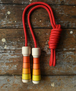 Mader Kreiselmanufaktur Children's Skipping Rope with Orange Handles placed on a wooden surface in the Babipur playroom. 