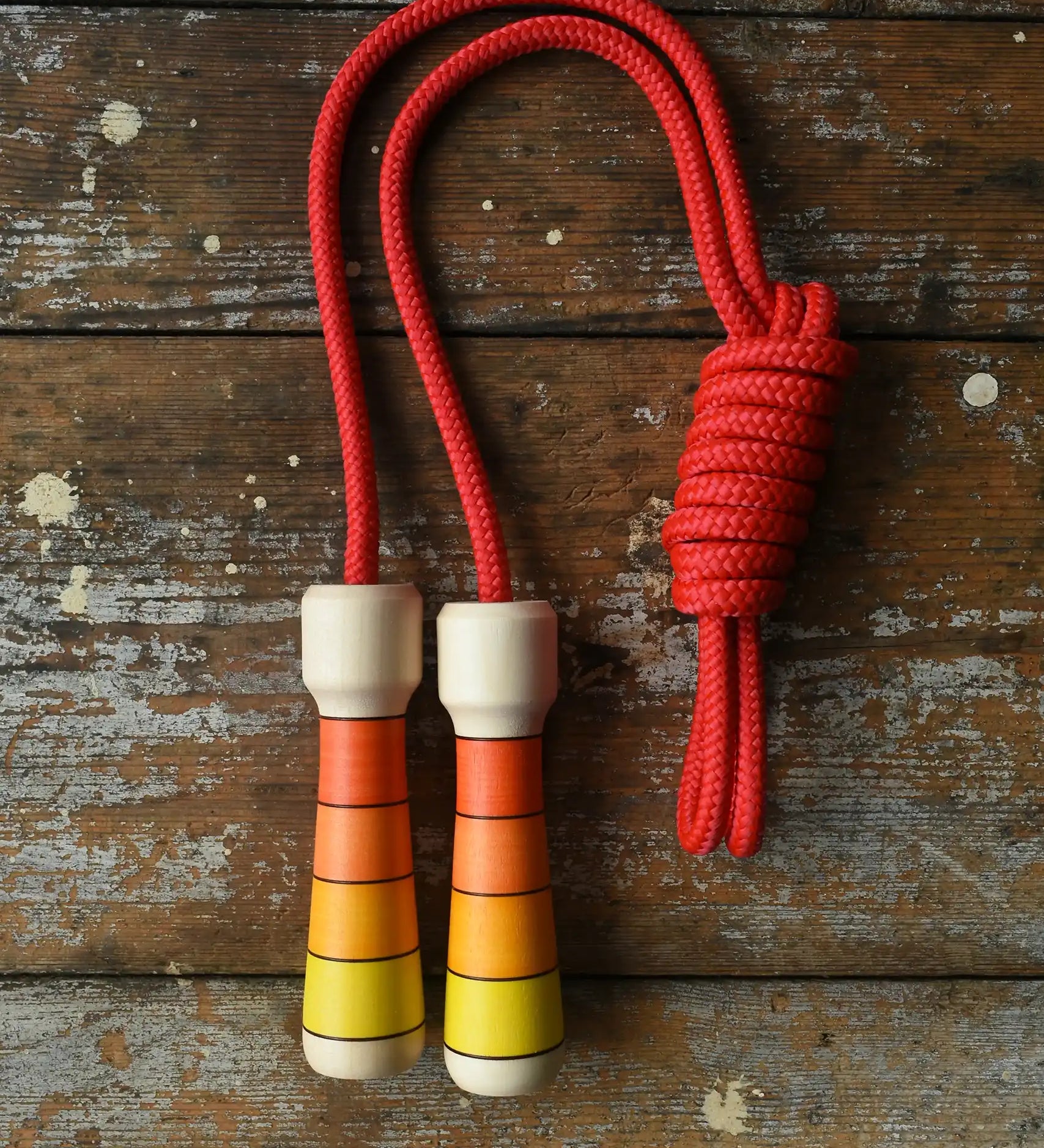 Mader Kreiselmanufaktur Children's Skipping Rope with Orange Handles placed on a wooden surface in the Babipur playroom. 