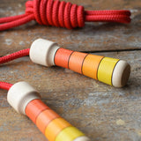 Mader Kreiselmanufaktur Children's Skipping Rope with Orange Handles placed on a wooden surface in the Babipur playroom. 
