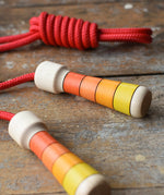 Mader Kreiselmanufaktur Children's Skipping Rope with Orange Handles placed on a wooden surface in the Babipur playroom. 