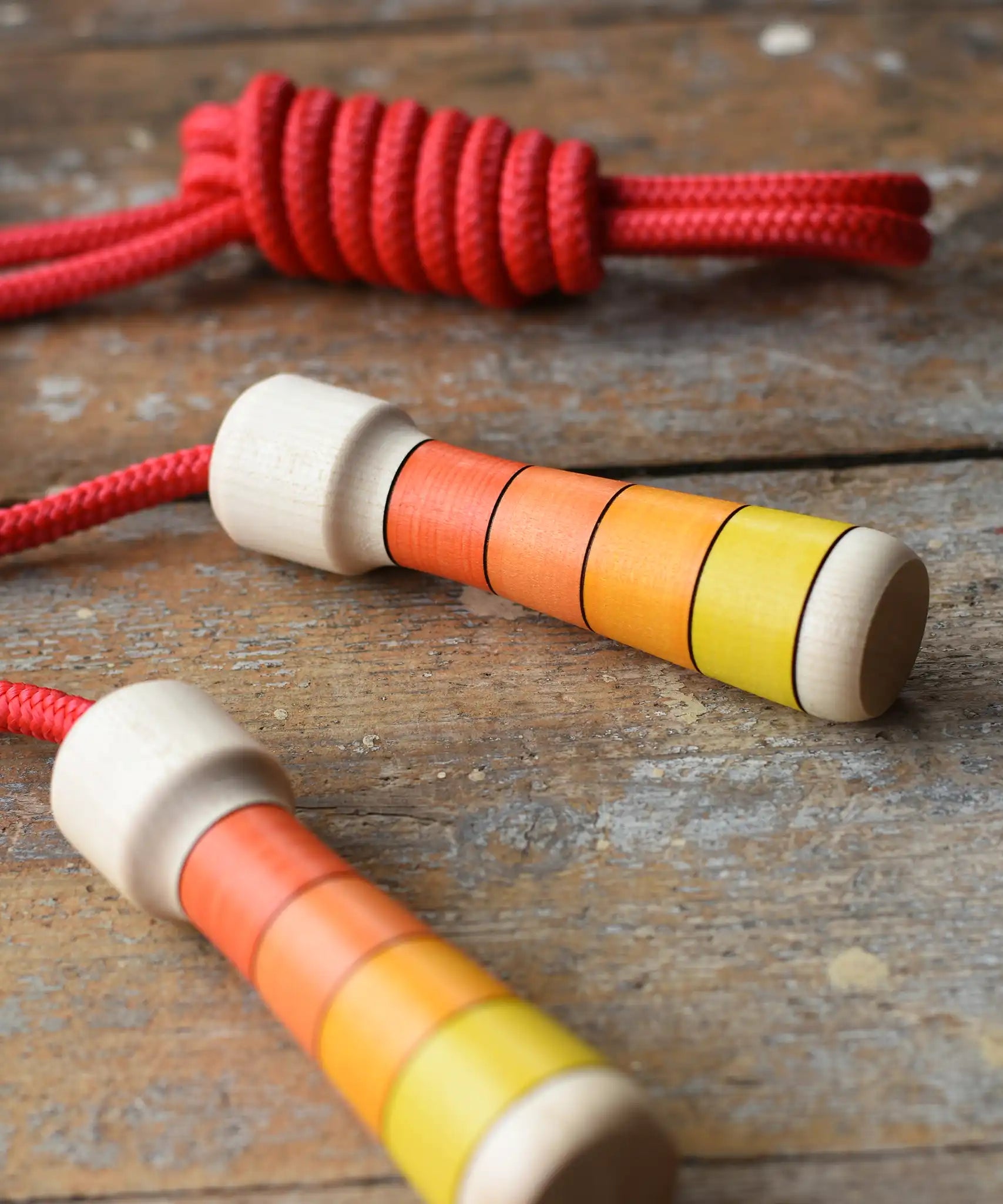 Mader Kreiselmanufaktur Children's Skipping Rope with Orange Handles placed on a wooden surface in the Babipur playroom. 