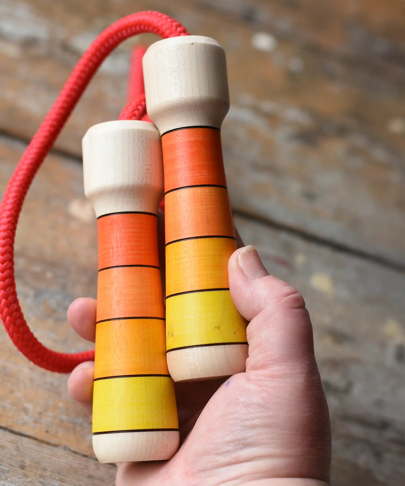 Mader Kreiselmanufaktur Children's Skipping Rope with Orange Handles in an adult's hand. 
