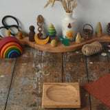 Mader Small Oak Spinning Plate placed on a wooden surface in the Babipur playroom. Grimm's celebration ring set up in the background.