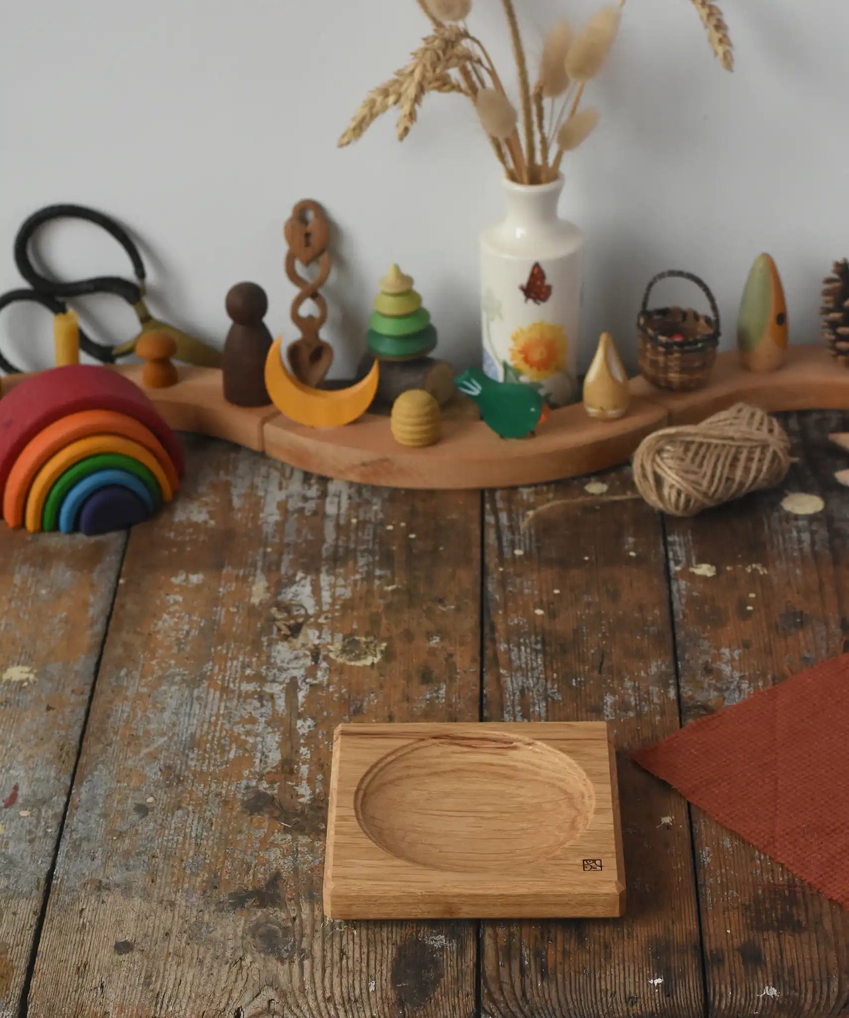 Mader Small Oak Spinning Plate placed on a wooden surface in the Babipur playroom. Grimm's celebration ring set up in the background.
