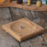 Mader Small Oak Spinning Plate with a miniature rainbow spinning top spinning on the board.