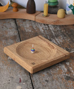 Mader Small Oak Spinning Plate with a miniature rainbow spinning top spinning on the board.