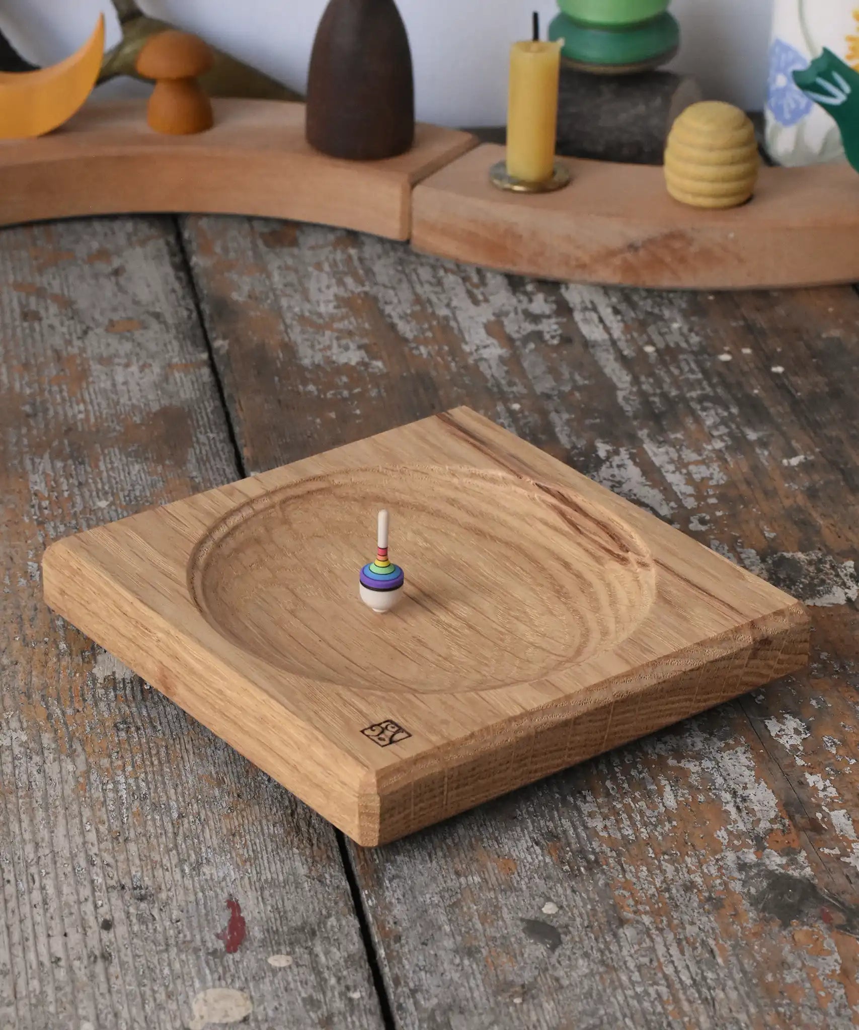 Mader Small Oak Spinning Plate with a miniature rainbow spinning top spinning on the board.