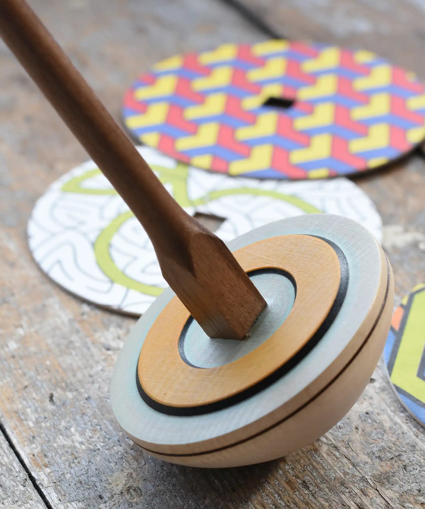 Mader 'So And So' DIY Spinning Top Set placed on a wooden desk in the Babipur playroom. Close up of square shaped base.