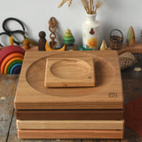 A stack of handmade Mader spinning plates in different woods, cherry, ash, walnut and oak placed on a wooden surface in the Babipur playroom. 