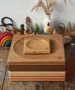 A stack of handmade Mader spinning plates in different woods, cherry, ash, walnut and oak placed on a wooden surface in the Babipur playroom. 