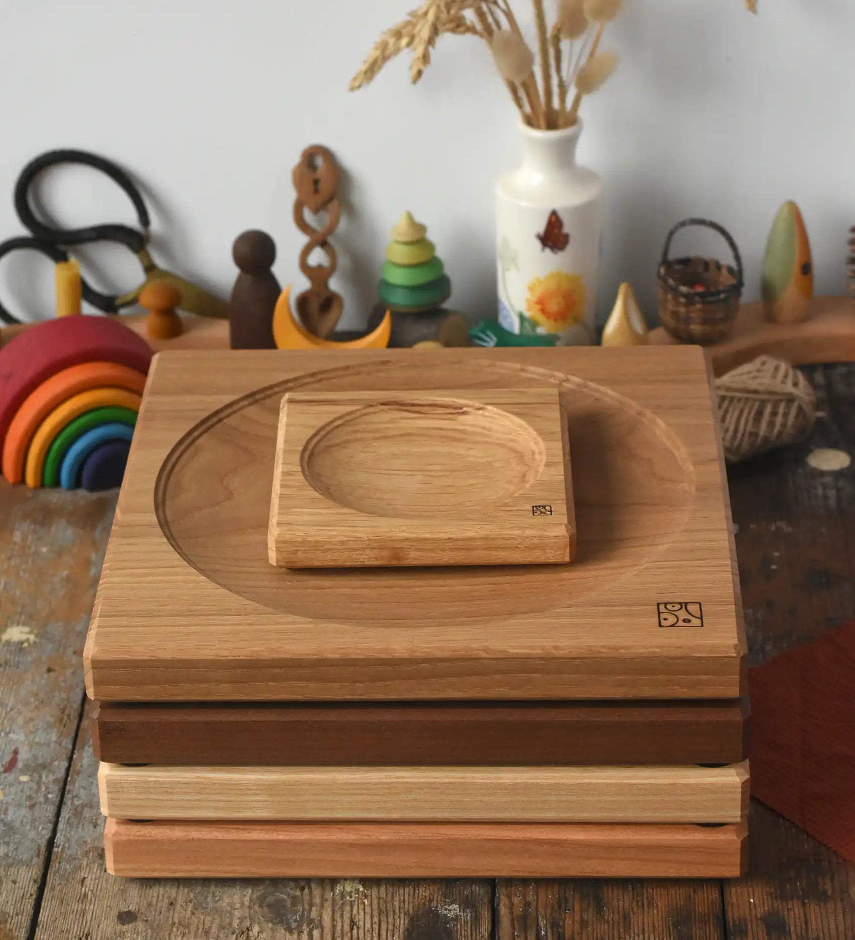 A stack of handmade Mader spinning plates in different woods, cherry, ash, walnut and oak placed on a wooden surface in the Babipur playroom. 